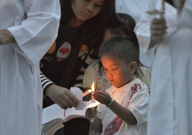 A boy helps light candles at Mass in Banda Aceh / CNS 