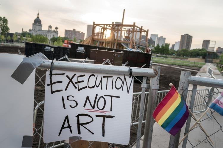 A protest sign against Sam Durant’s “Scaffold” sculpture on the perimeter fence of the Walker Art Center's sculpture garden / flickr - Lorie Shaull