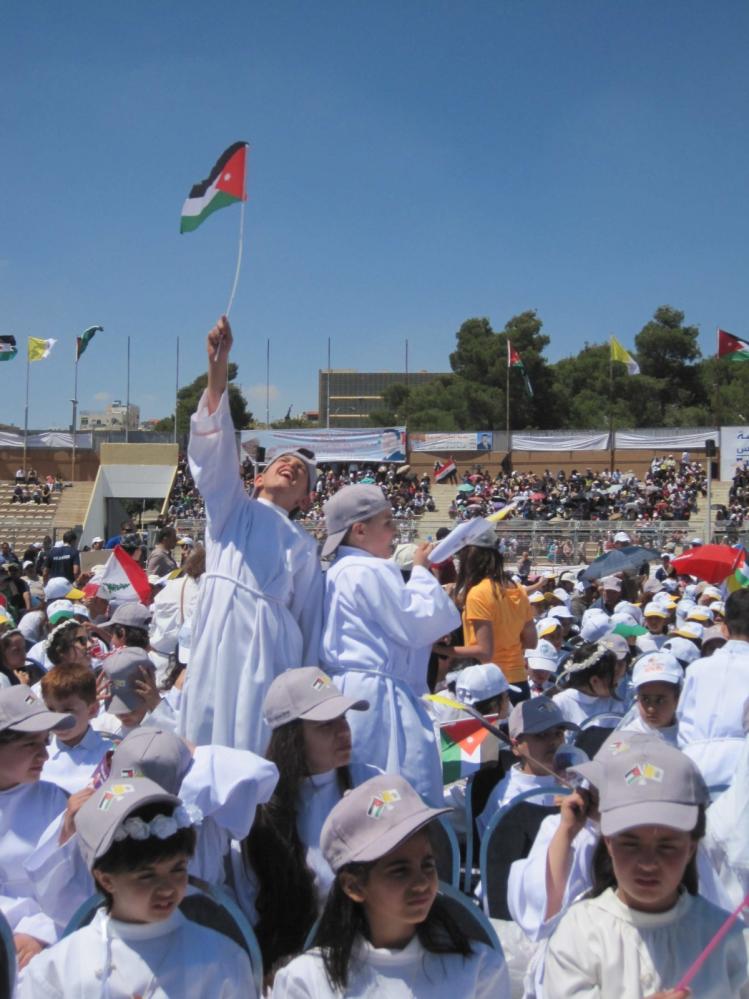A First Communicant waves a Jordan flag at the Pope's Mass in Amman.