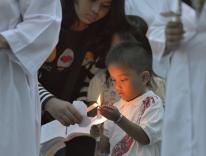 A boy helps light candles at Mass in Banda Aceh / CNS 